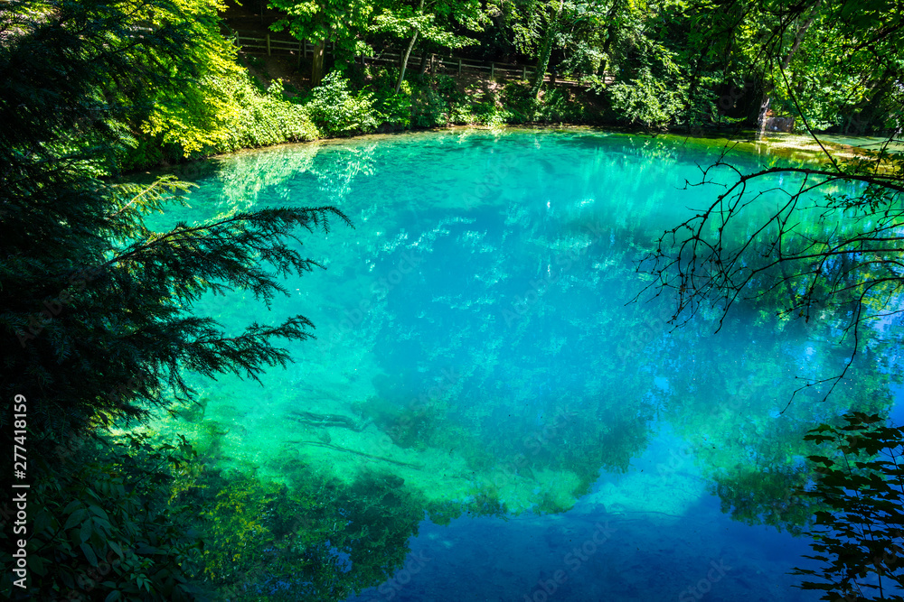 Germany, Blue glassy waters of source blue pot (blautopf) in blaubeuren, a natural monument inside green forest of swabian jura landscape near ulm