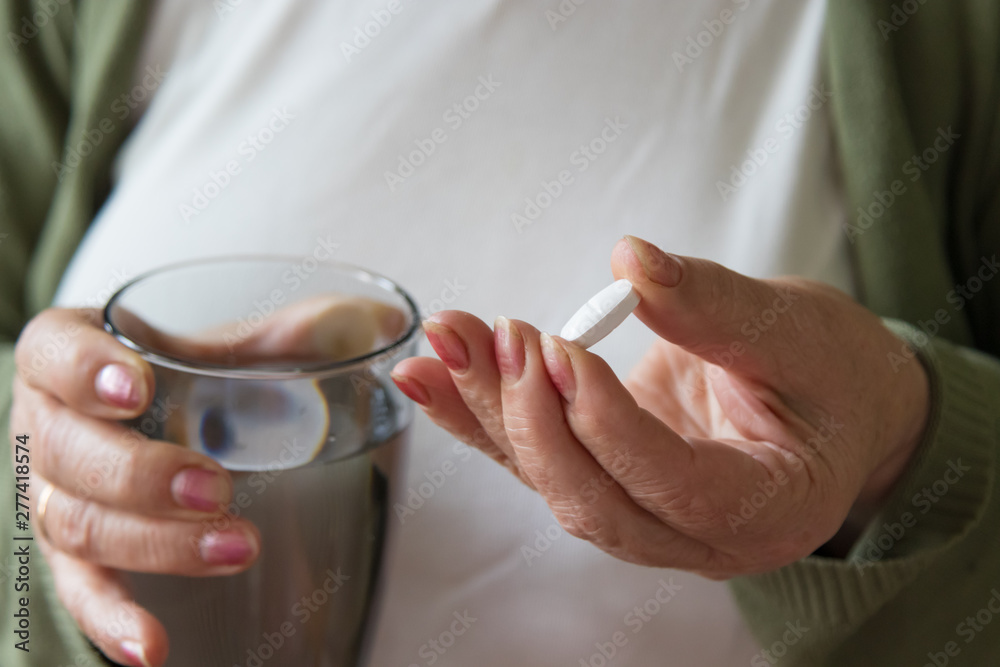 senior hand with pills and glass of water senior hand with pills and glass of water