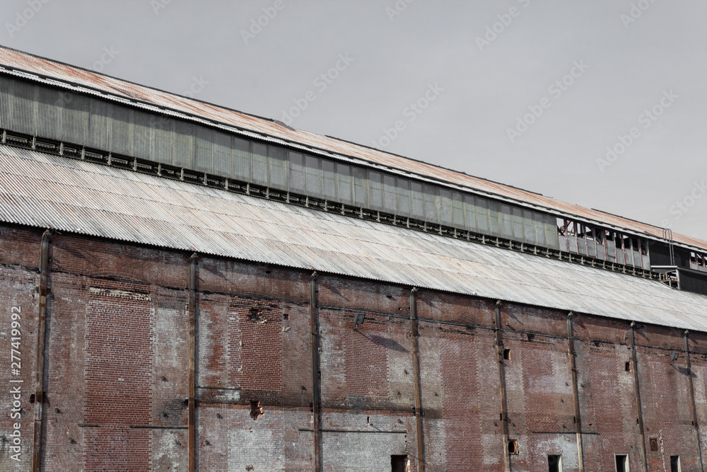 Old brick warehouse building with corrugated metal roof, horizontal aspect