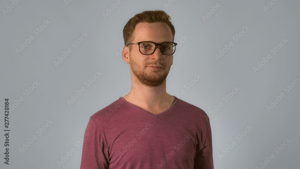 caucasian guy with red hair put on eyeglasses. handsome redhead men wearing in casual t- shirt. smart young caucasian man on grey background caucasian guy with red hair put on eyeglasses. handsome redhead men wearing in casual t- shirt. smart young caucasian man on grey background