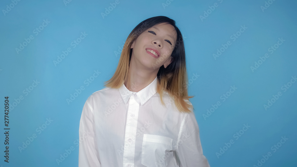 young asian woman dancing funny dance on blue background in studio. attractive millennial girl wearing white casual shirt looking at the camera smiling young asian woman dancing funny dance on blue background in studio. attractive millennial girl wearing white casual shirt looking at the camera smiling