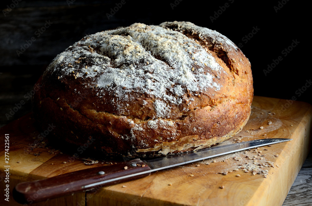 Homemade rustic bread with sesame on a wooden table.