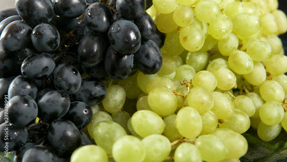Green and blue bunch of grapes lying on a platter. 4K UHD 3840x2160 Video Clip