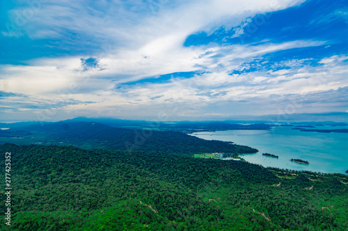 Aerial view of Langkawi island's forest and coastal area with blue sky background