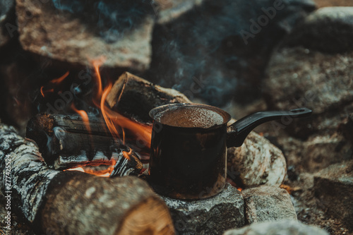 Making coffee in cezve on the fireplace when camping or hiking. coffee on campfire