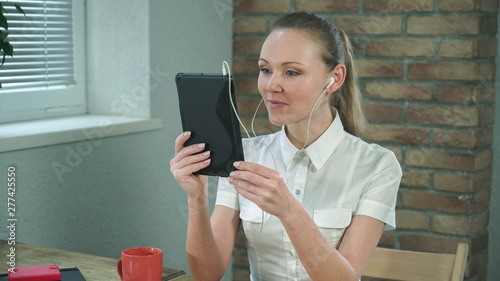 Woman have video chatting with friend on her digital tablet. Sits in the officce by working place