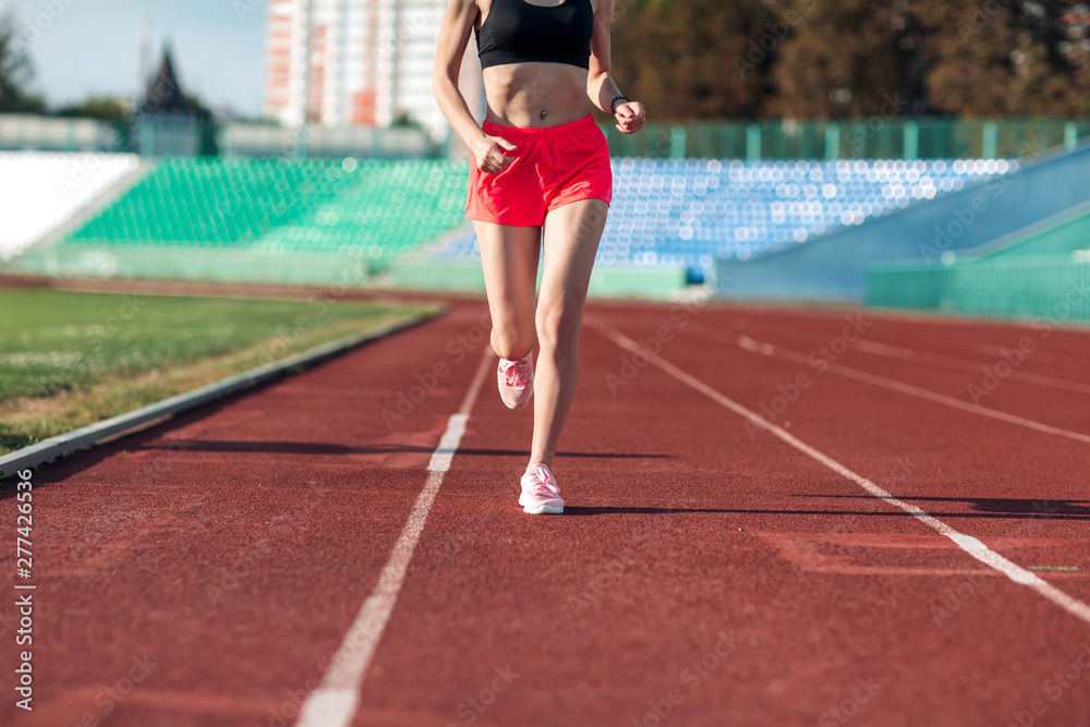 Sport. Woman fitness legs running on stadium. Close up of feet of a runner. Woman fitness jog workout wellness concept. Athlete runner feet running on running track.