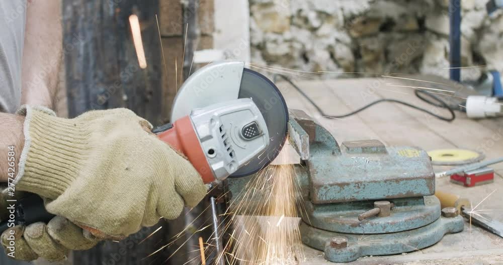 Découpe d'une pièce métallique avec une disqueuse dans un attelier 