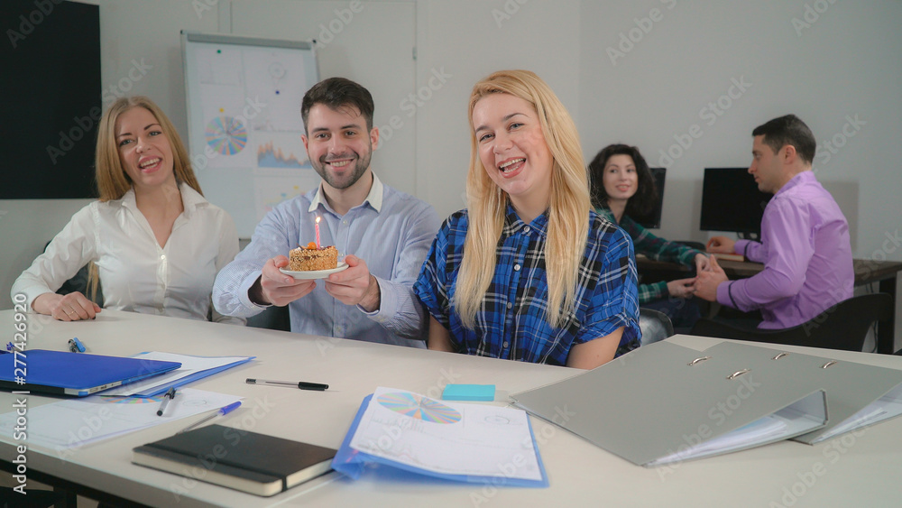 Obraz premium portrait three co workers sitting at the table posing looking at the camera. On the background staff talking with happy smile.