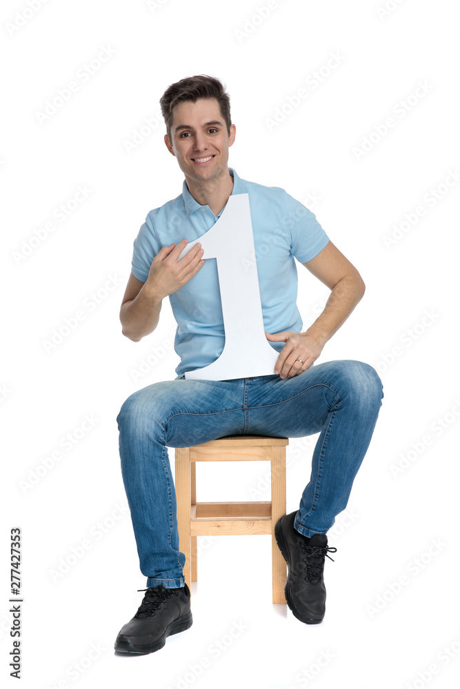 Happy young man holding a number one and smiling