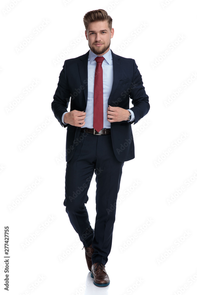 Motivated casual guy walking and fixing his jacket Motivated casual guy walking and fixing his jacket