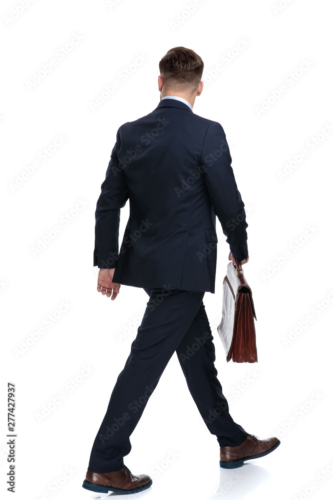 Rear view of a walking businessman holding his briefcase Rear view of a walking businessman holding his briefcase
