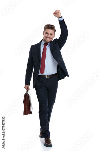 Happy businessman stepping and celebrating while holding a briefcase