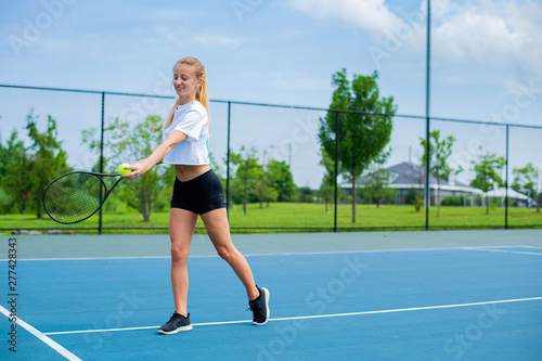 Beautiful woman with tennis racket playing tennis on blue court © Dmytro Flisak
