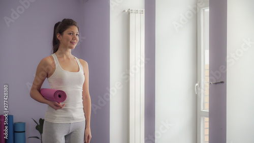 Girl standing with yoga mat getting ready to exercise. Soft panorama