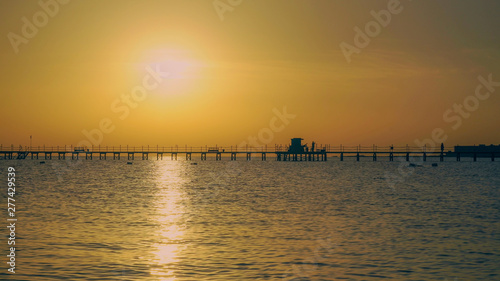 Sunrise in the sea, people are walking along the pier video UHD