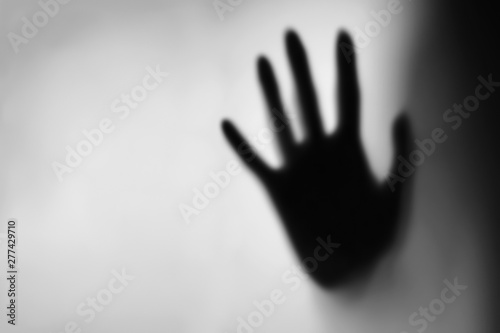 Blurry female hand reaching out and touching glass with Blue light