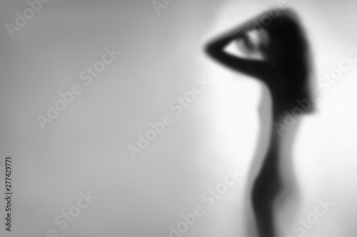 Blurry silhouette of beautiful woman behind glass