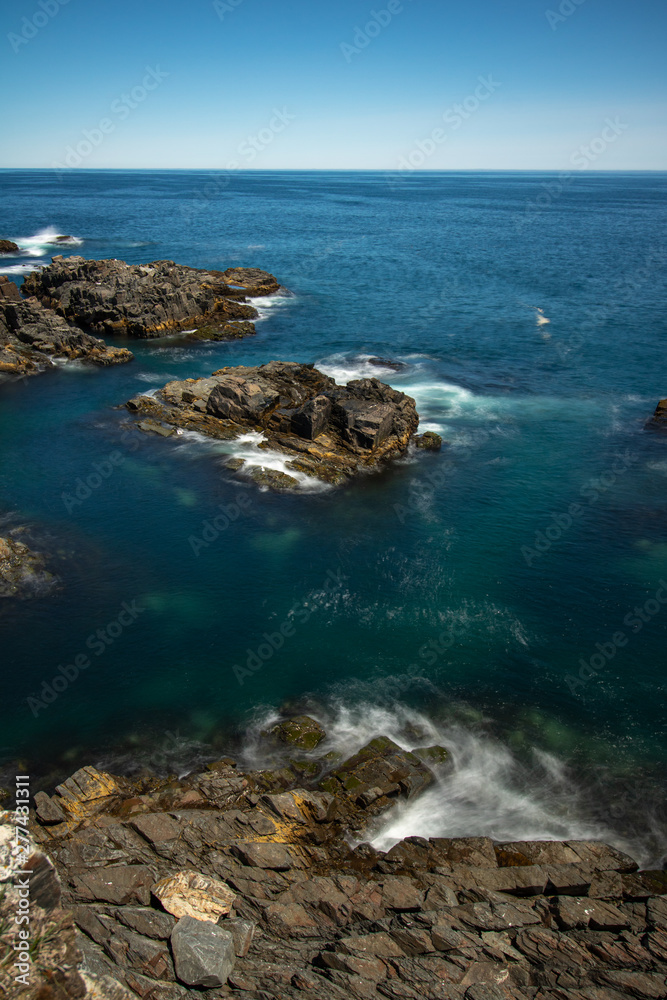 Crystal clear pristine blue water surrounded by a rugged rocky coastline. Elliston, Newfoundland Canada.  