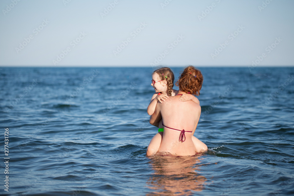 young girl in red glasses and a green bathing suit resting on the sea. childhood and sea air young girl in red glasses and a green bathing suit resting on the sea. childhood and sea air