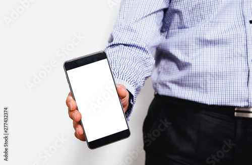 Fototapeta Naklejka Na Ścianę i Meble -  Phone in hand with a blank screen. A man dressed in a business shirt holds in his hand a phone with a blank display. Content completion concept.