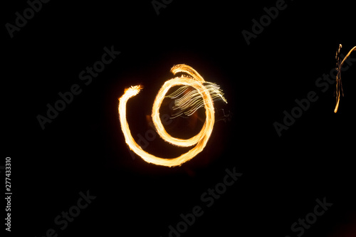 The artist shows a fire show at night spinning torches, circles of fire and loops