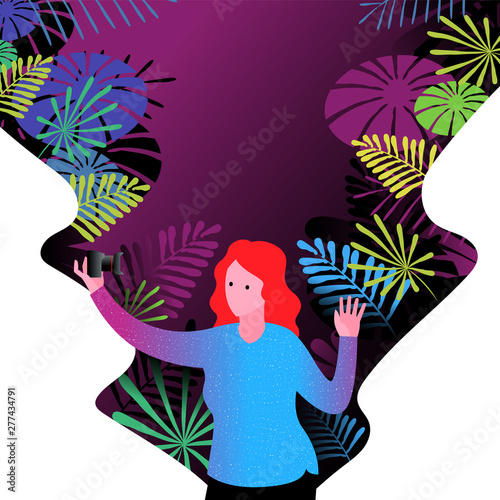 Woman taking selfie using digital camera in front of colorful vegetation.