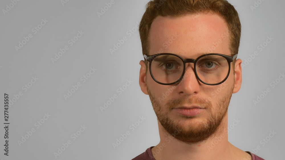 close up face caucasian guy with red hair put on eyeglasses. handsome ginger men wearing in casual t-shirt. smart young caucasian man on grey background close up face caucasian guy with red hair put on eyeglasses. handsome ginger men wearing in casual t-shirt. smart young caucasian man on grey background