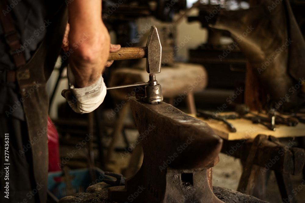 A blacksmith is forging hot iron on an anvil