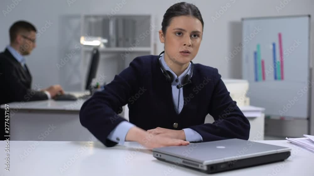 Nervous female call manager taking off headset and closing laptop, hard day Nervous female call manager taking off headset and closing laptop, hard day