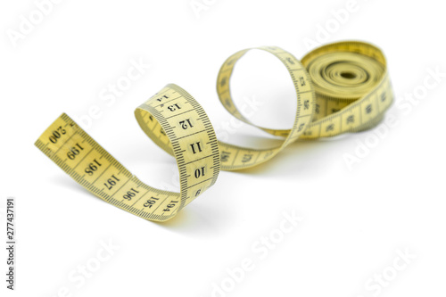 The yellow measuring centimetric tape curtailed by a spiral on a white background. Sewing accessories