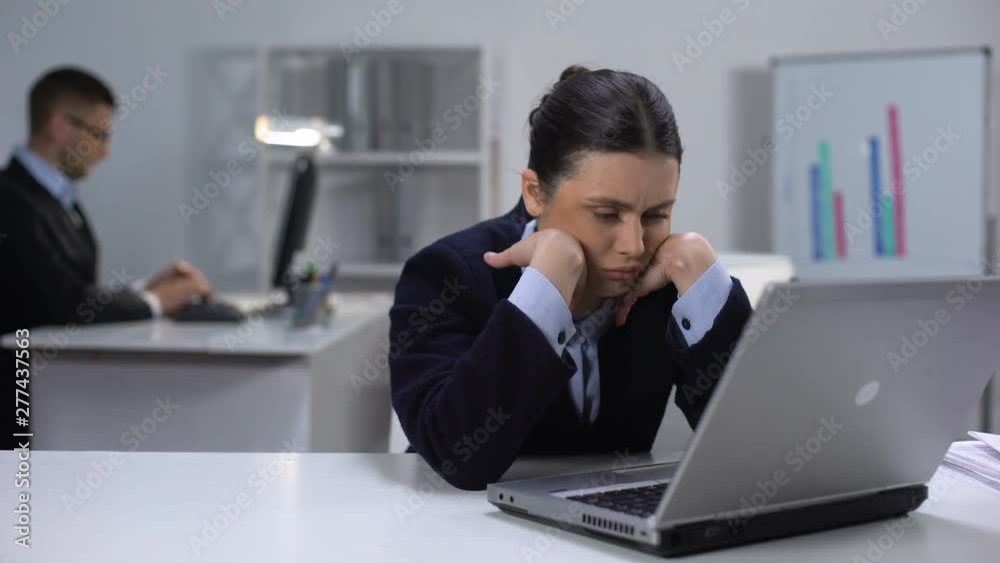 Bored female manager texting on laptop, procrastination issue, avoiding work Bored female manager texting on laptop, procrastination issue, avoiding work