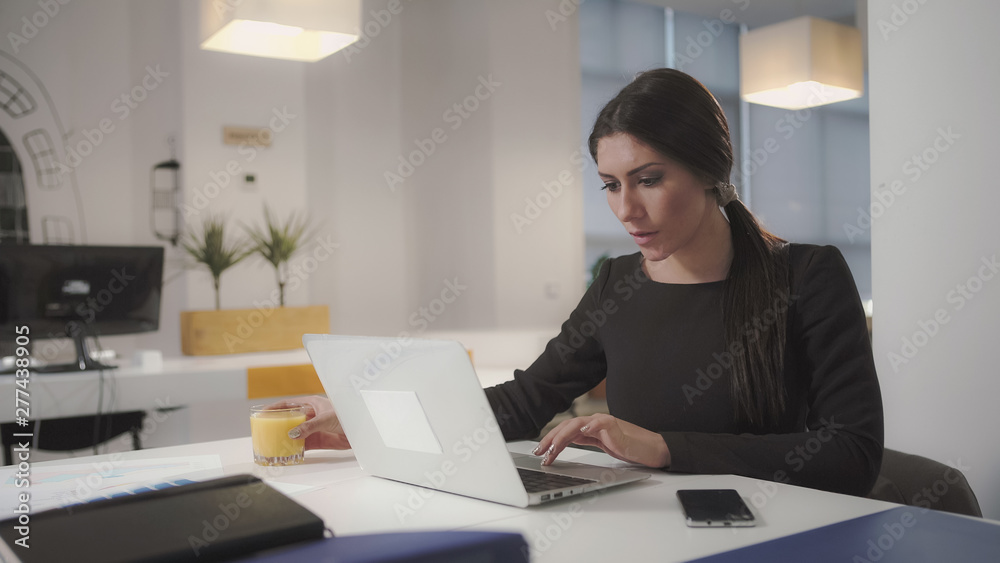 A woman working at the computer and drinking orange juice. UHD A woman working at the computer and drinking orange juice. UHD