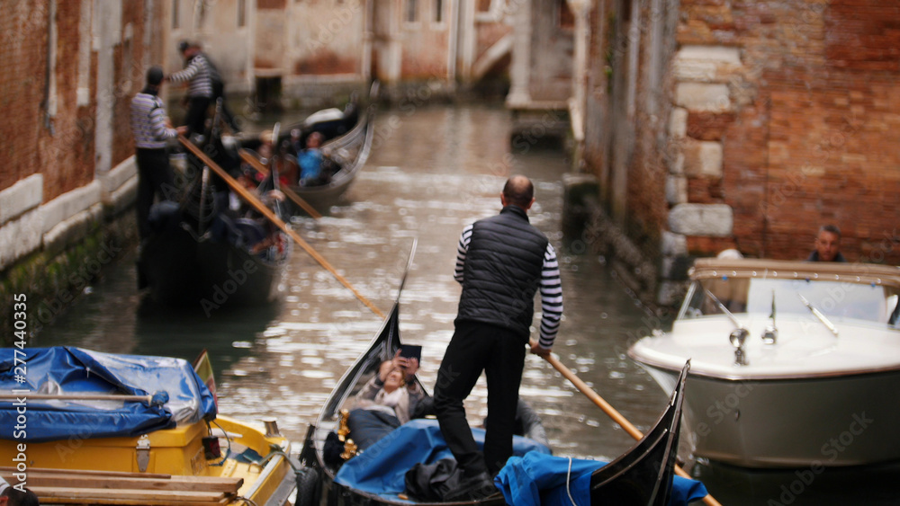 The water channel of Venice - men are rowing on a rowboat along the river