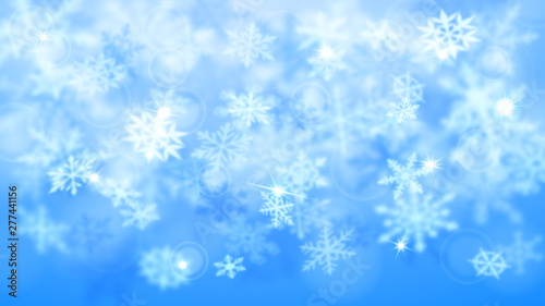 Christmas blurred background of complex defocused big and small falling snowflakes in light blue colors with bokeh effect