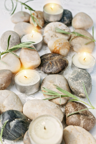SPA vertical concept. Sea pebbles, bamboo shoots, scented candles, sea salt on a light wooden background