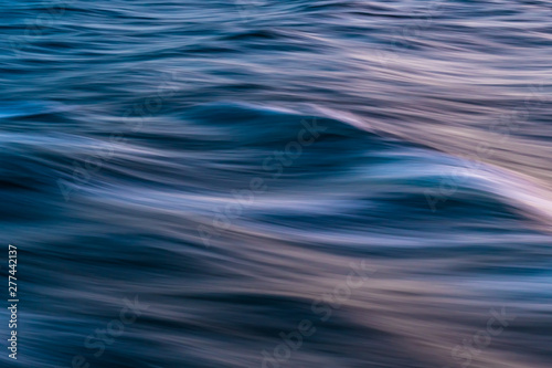 Gentle soothing silky flowing natural ocean water movement. Abstract background motion blur. Serene and peaceful deep blue sea in nature.