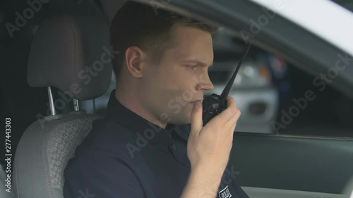 Patrolman transmitting information using two-way radio, waiting for instructions