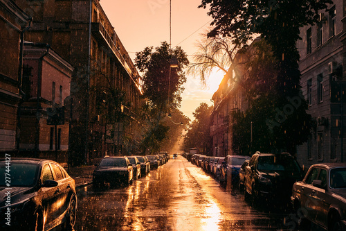 Parked cars in midtown of summer city Voronezh, summer rain and sunset sun in old European city © DedMityay