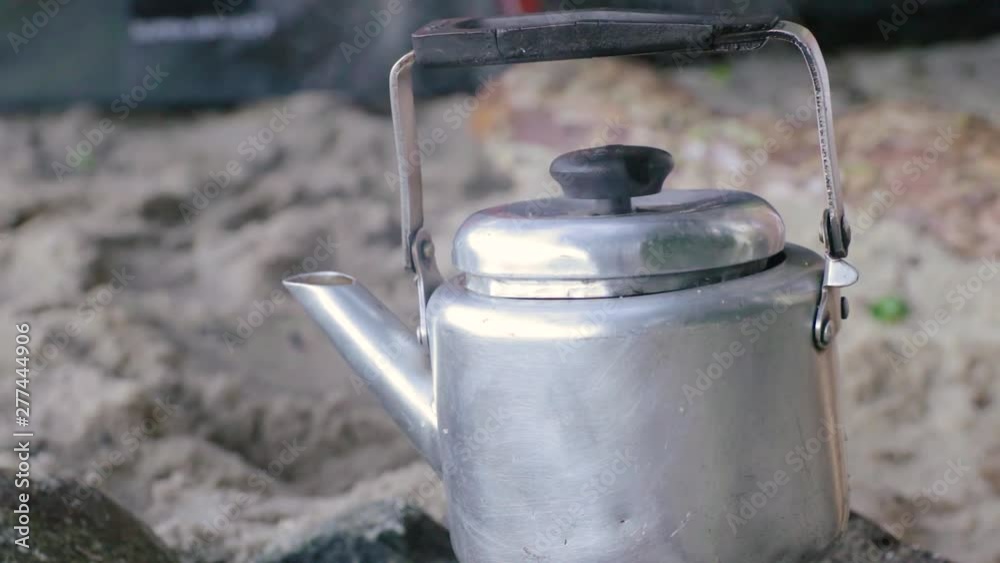 A pan making water hot to make some coffee, in camping at beach during a great sunny day, slow motion