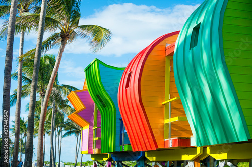 Bright scenic view of colorful new lifeguard towers standing in a row with the shadows of palm trees in South Beach, Miami, Florida, USA © lazyllama