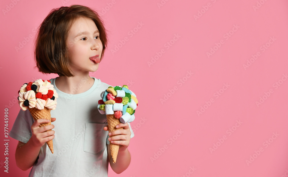 Teen girl kid holding eating licking two big ice cream in waffles cone with tasty toppings put her tongue out at somebody Teen girl kid holding eating licking two big ice cream in waffles cone with tasty toppings put her tongue out at somebody