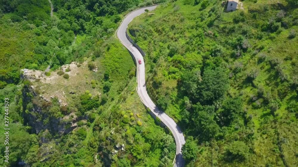 Aerial view top down of winding serpentine road, drone camera follow the car driving on zig-zag twisted road in green mountain gorge Aerial view top down of winding serpentine road, drone camera follow the car driving on zig-zag twisted road in green mountain gorge