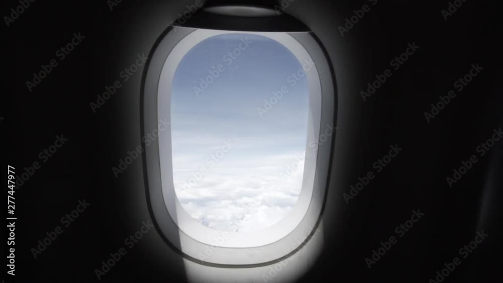 Slow motion dolly out or pullout of a plane window in the cabin with amazing blue sky and white clouds