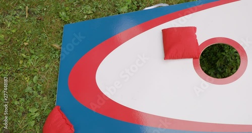Playing Cornhole Game in Yard with Red, White and Blue Board and Bags