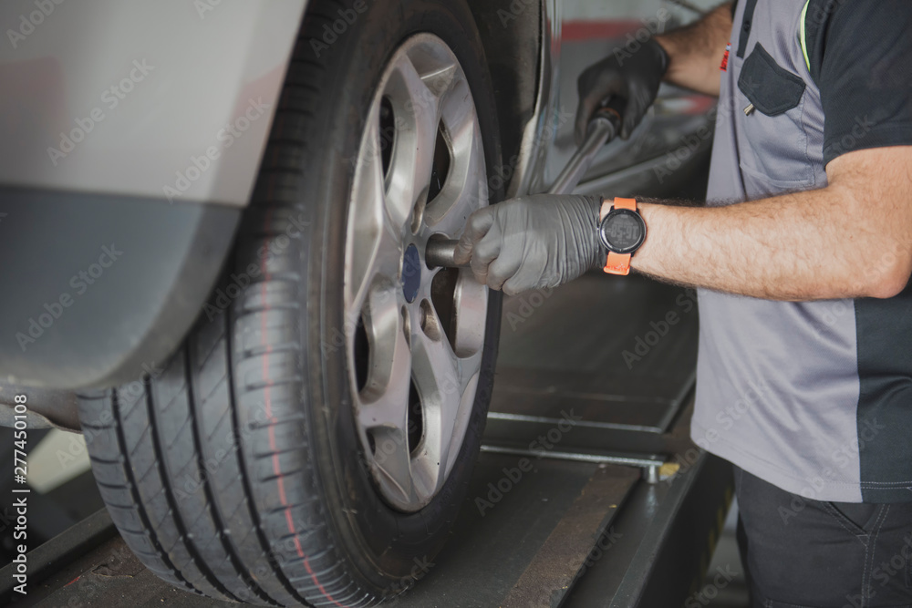 car mechanic screwing a car wheel with a lever car mechanic screwing a car wheel with a lever