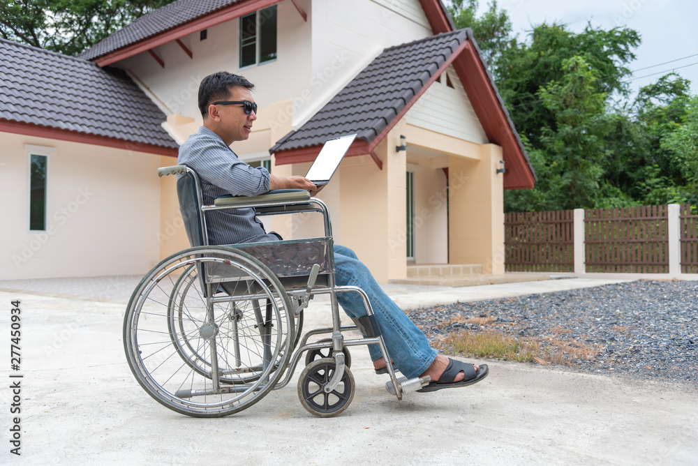 Disabled middle-age Asian person in the wheelchair work at home with laptop. Disabled middle-age Asian person in the wheelchair work at home with laptop.