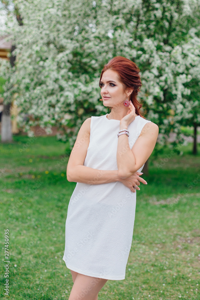 Charming woman wearing beautiful white dress under the apple tree Charming woman wearing beautiful white dress under the apple tree