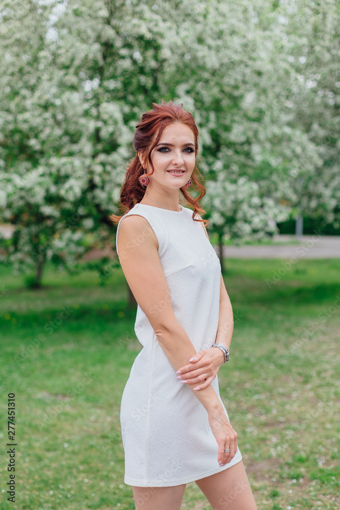 Charming woman wearing beautiful white dress under the apple tree Charming woman wearing beautiful white dress under the apple tree