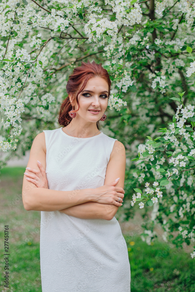 Charming woman wearing beautiful white dress under the apple tree Charming woman wearing beautiful white dress under the apple tree